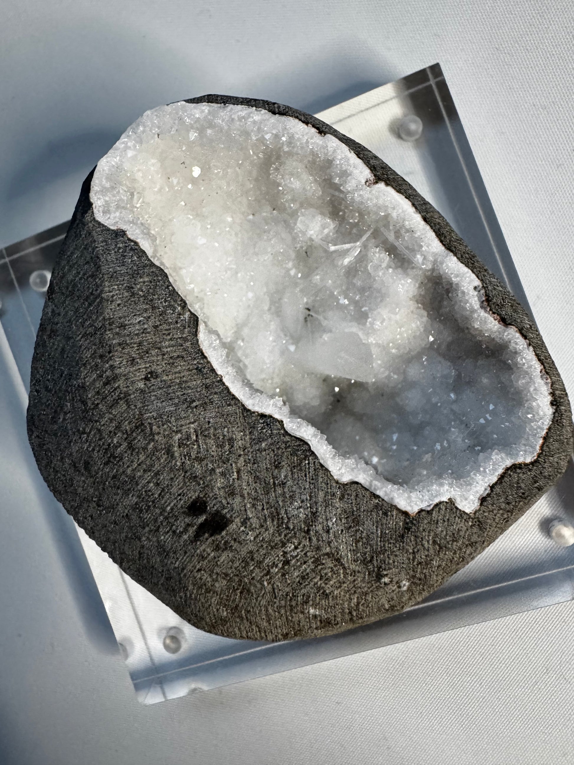 Scolecite & Quartz Crystal Geode with radiant white needle-like crystals inside a dark gray stone shell, ideal for mineral collectors and crystal healing.