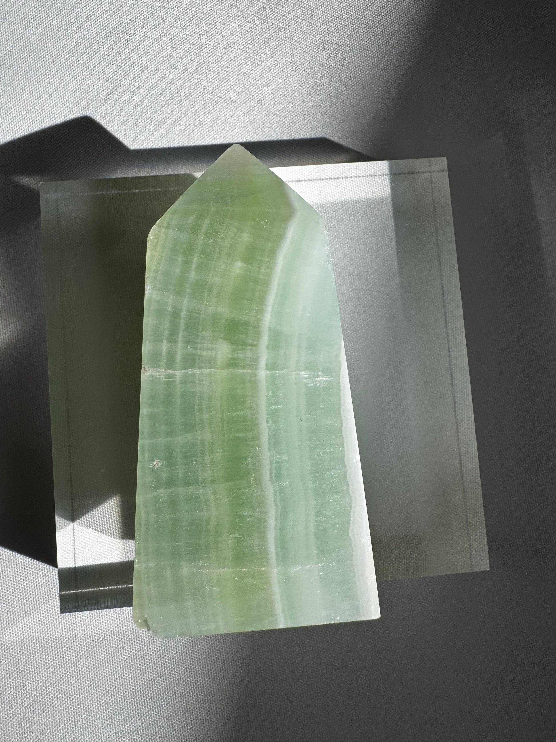 Pistachio Calcite Mini Tower #3 with blue-green hues and white striations, displayed upright on a clear acrylic base for collectors.