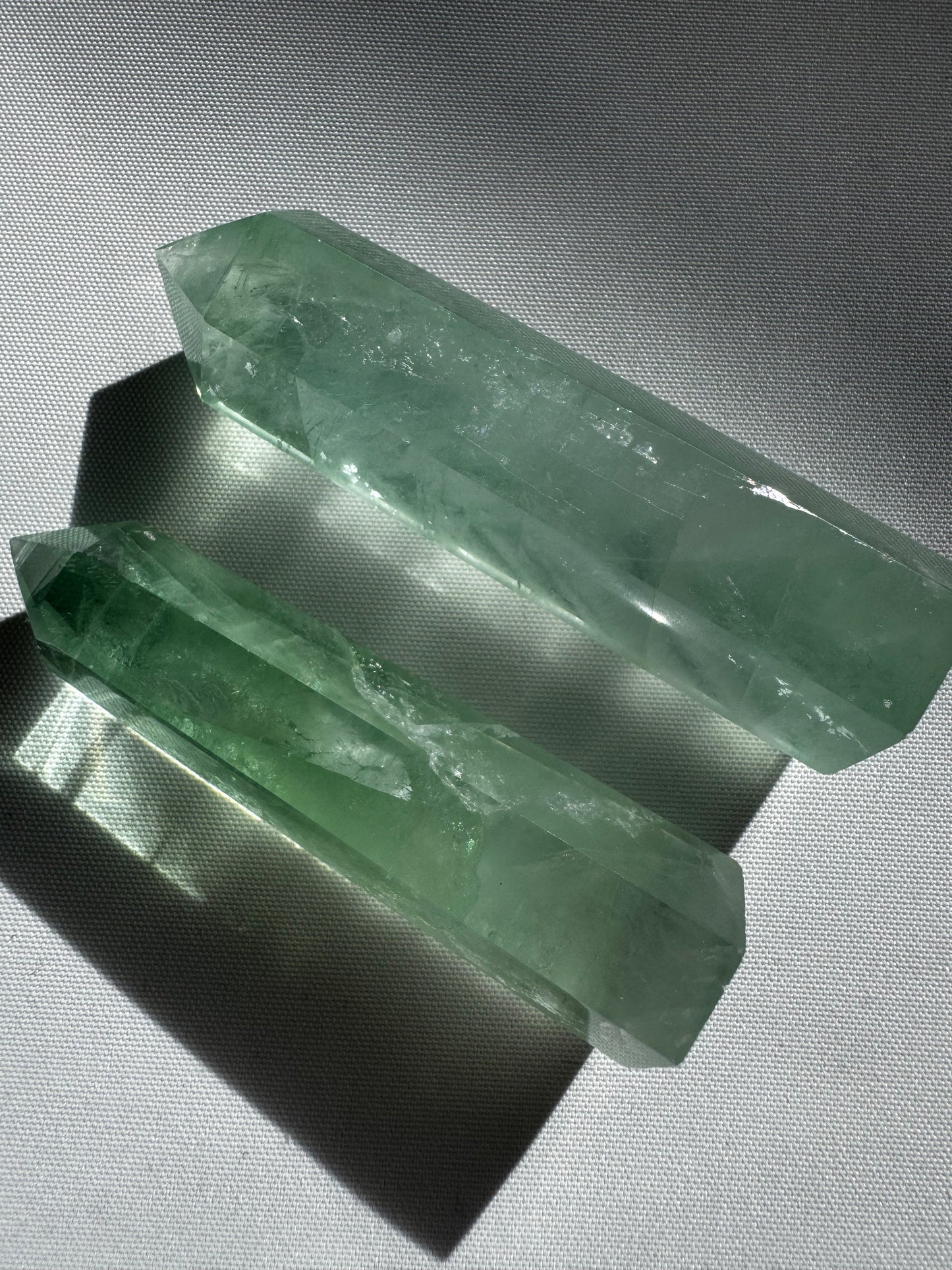 Two Green Fluorite Crystal Points , showcasing their translucent green hues and polished facets for healing energy use.
