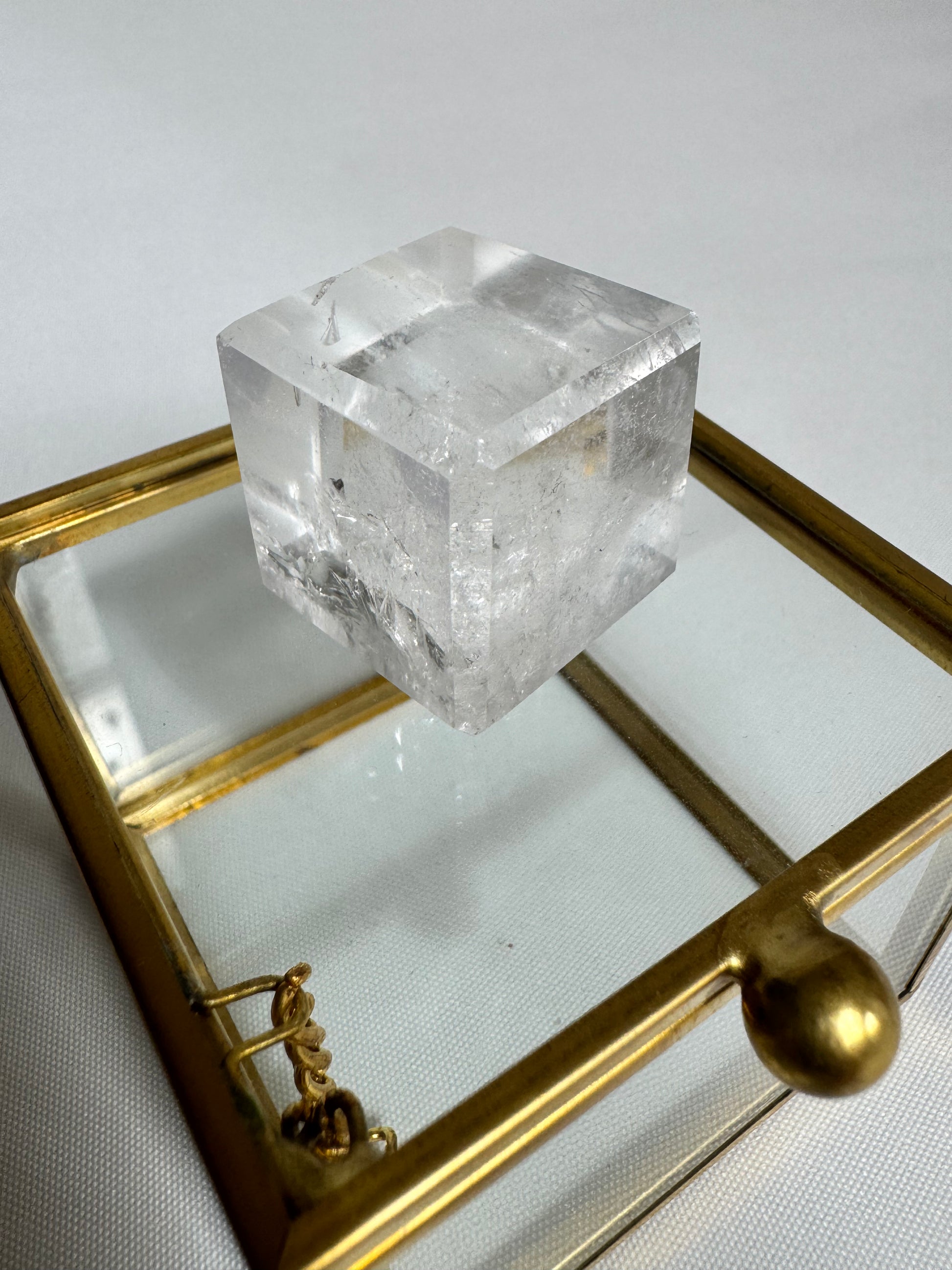 Lemurian Hexahedron Cube featured on a brass-trimmed glass box, showcasing its clarity and sacred geometry for spiritual use.