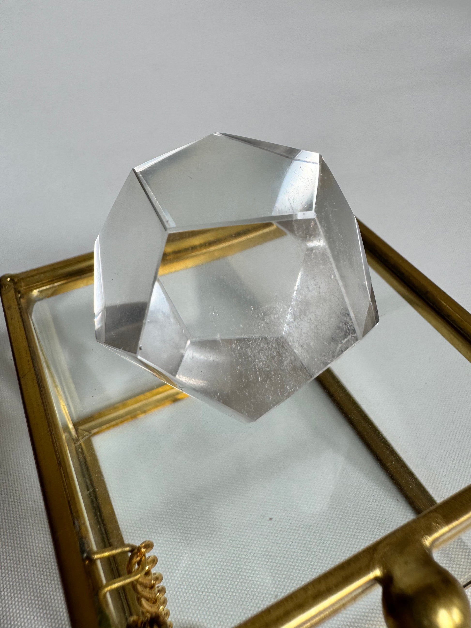 Polished Lemurian Quartz Octahedron displayed on glass box, reflecting light for energy alignment and focus.