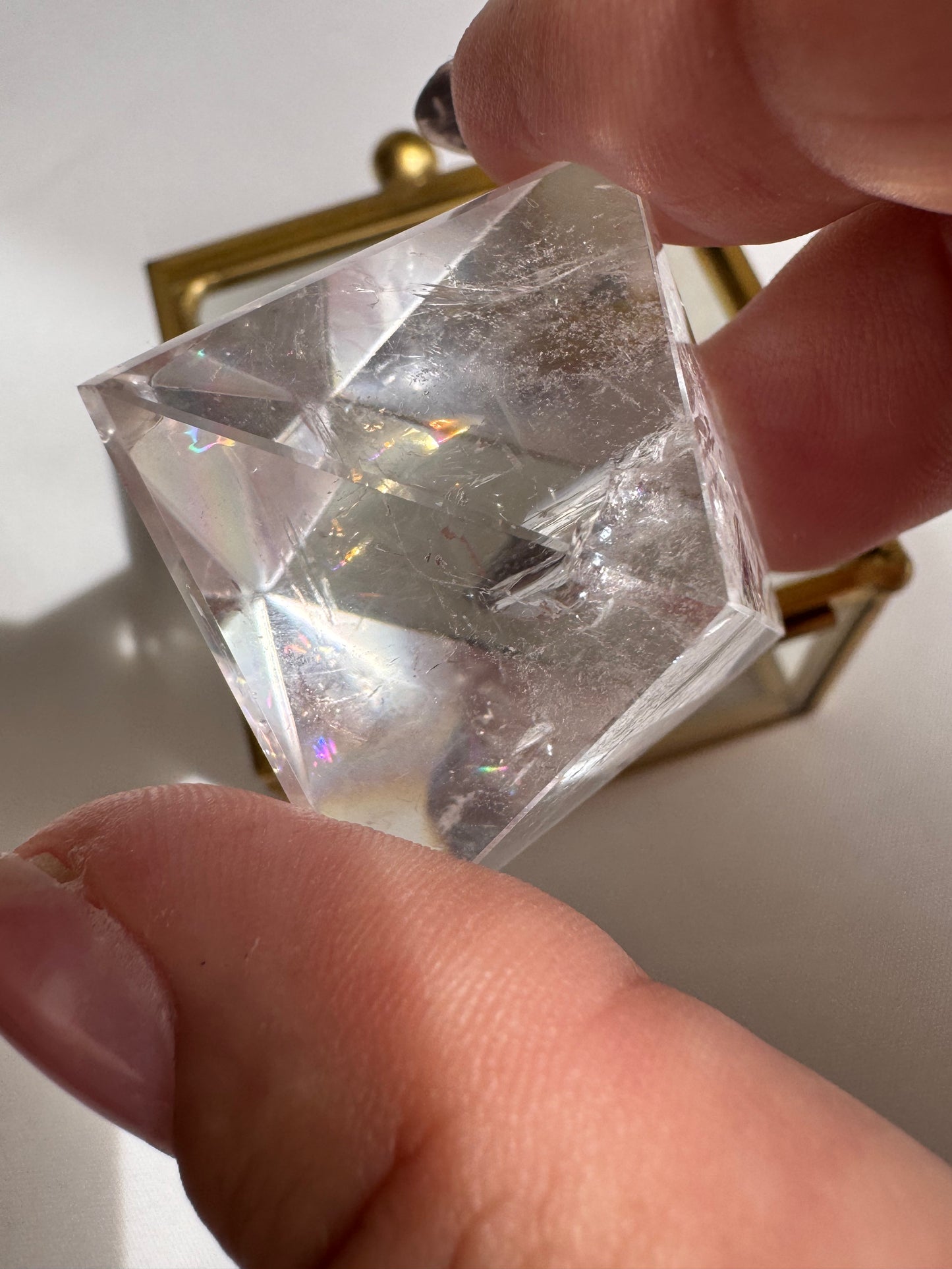 Hand holding Lemurian Quartz Octahedron with light reflections, symbolizing clarity and multidimensional energy.