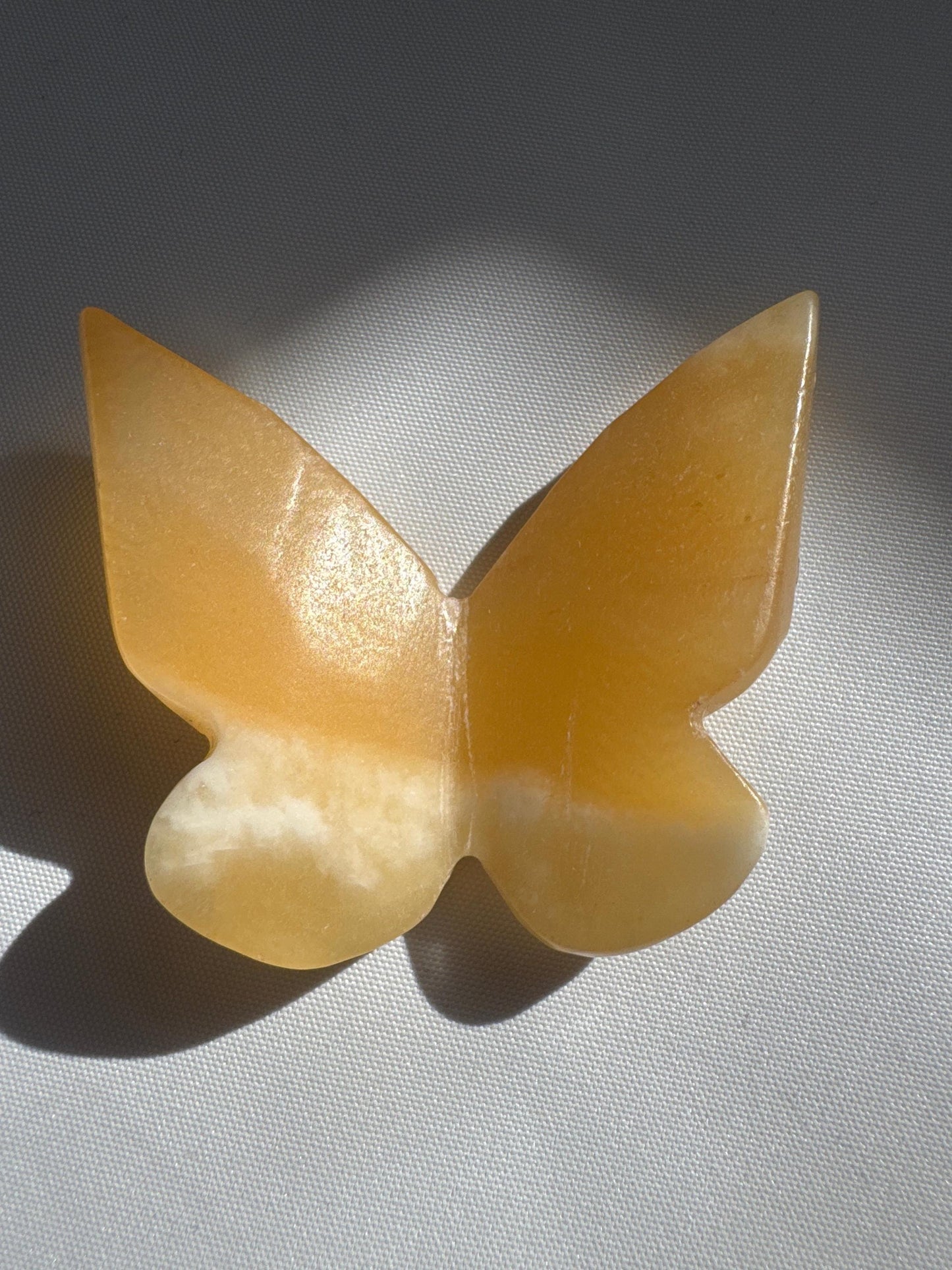 Single Orange Calcite Crystal 3D Butterfly with soft yellow-orange hues, carved in a symmetrical butterfly shape for collectible display.