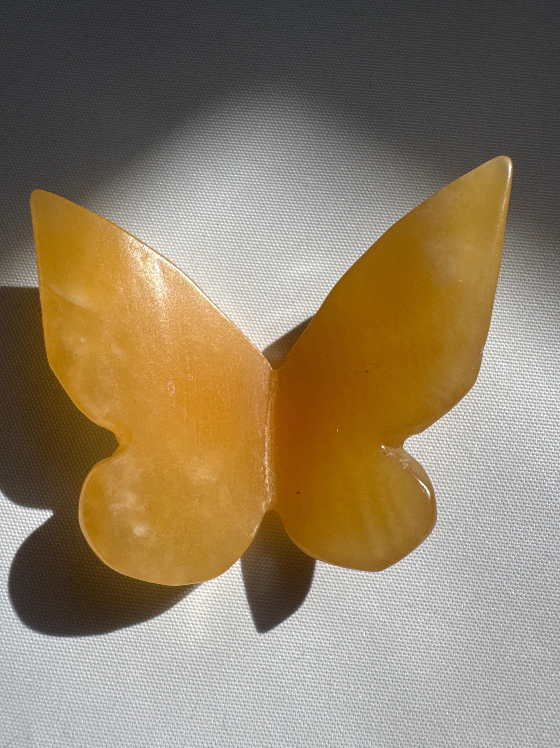 Close-up of Orange Calcite Crystal 3D Butterfly featuring translucent orange tones and polished surface, ideal for rock and crystal collectors.