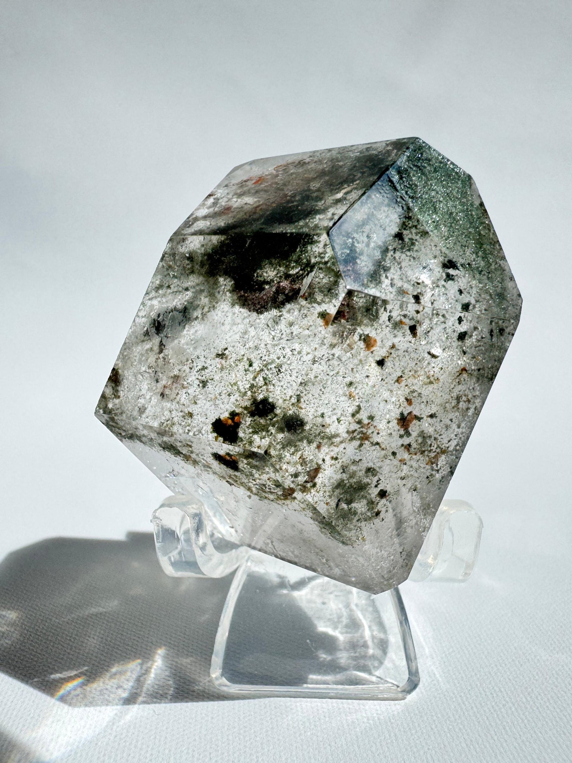 Lodalite Freeform displayed on a clear stand, showcasing internal landscapes. A unique Garden Quartz crystal from Healing Crystals NZ.