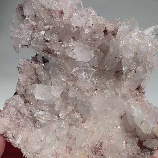 Handheld Pink Lithium Lemurian Seed Crystal Quartz Cluster with shimmering clarity and rose tones, perfect for emotional healing and display.