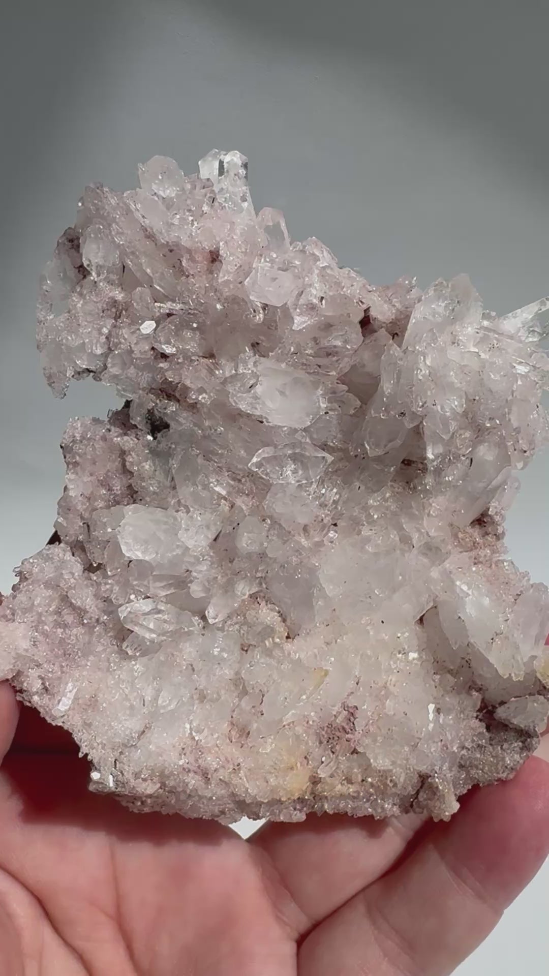 Handheld Pink Lithium Lemurian Seed Crystal Quartz Cluster with shimmering clarity and rose tones, perfect for emotional healing and display.