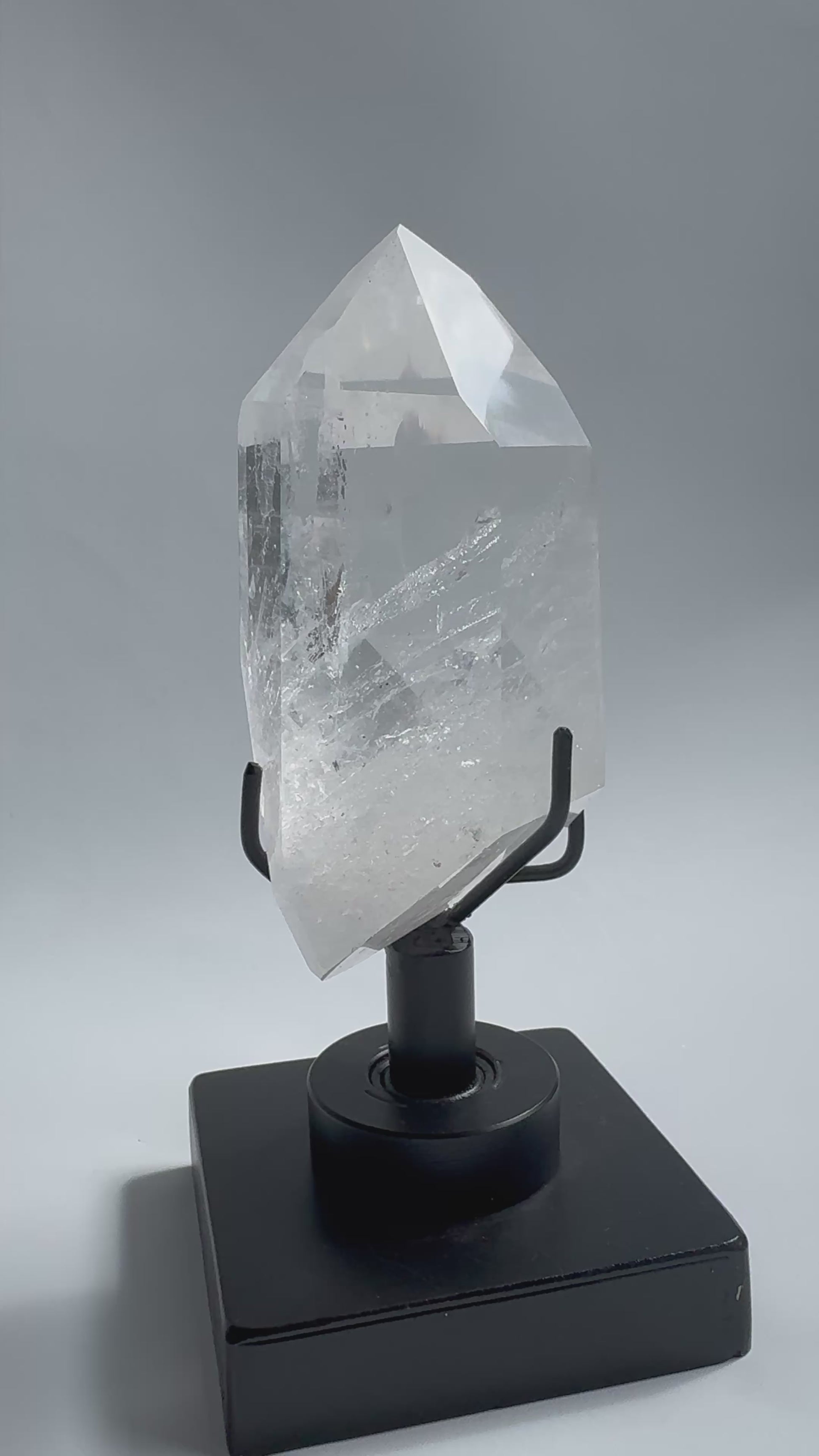 Clear Lemurian Quartz Crystal on sleek rotating base, showcasing natural striations and polished facets. A premium Quartz Crystal on Stand for collectors.