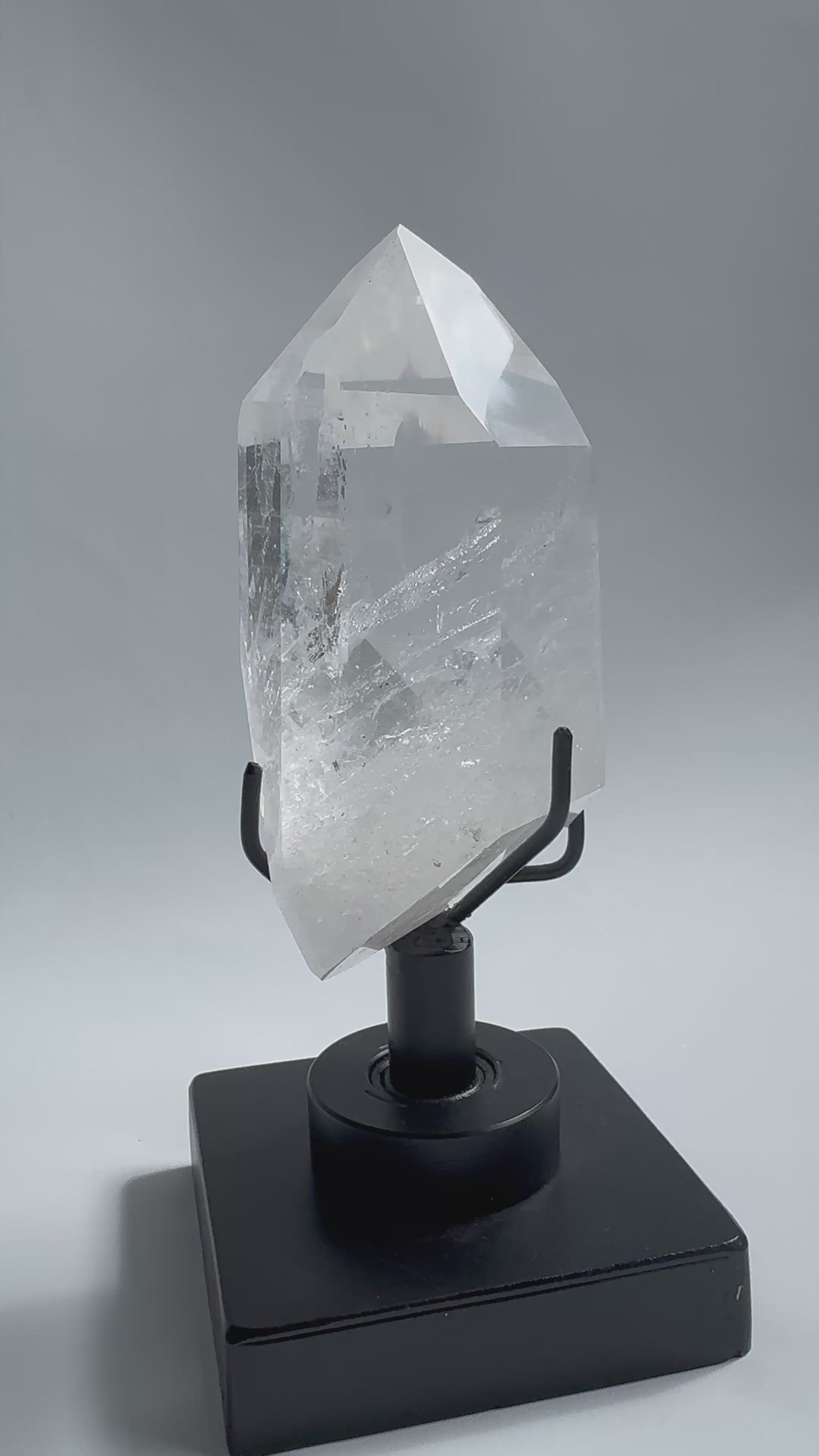 Clear Lemurian Quartz Crystal on sleek rotating base, showcasing natural striations and polished facets. A premium Quartz Crystal on Stand for collectors.