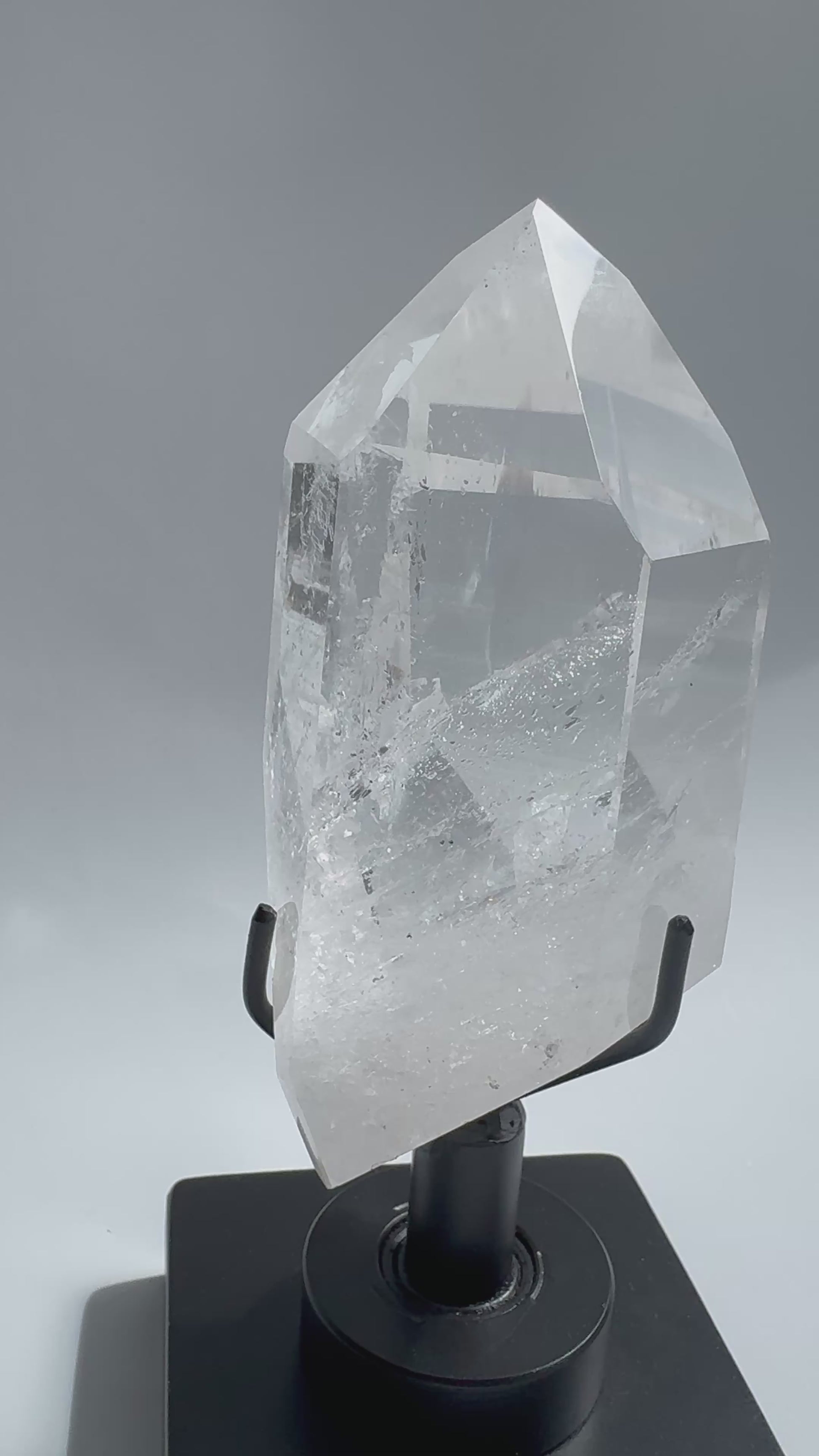 Lemurian Quartz Crystal with polished point and visible inclusions, mounted on a rotating black stand. A statement gemstone from Bahia, Brazil.